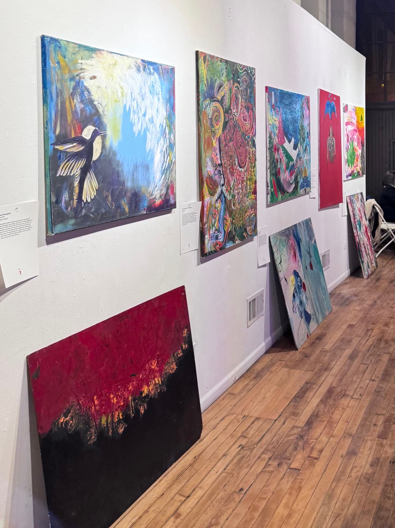 Paintings by community artists hung along a gallery wall