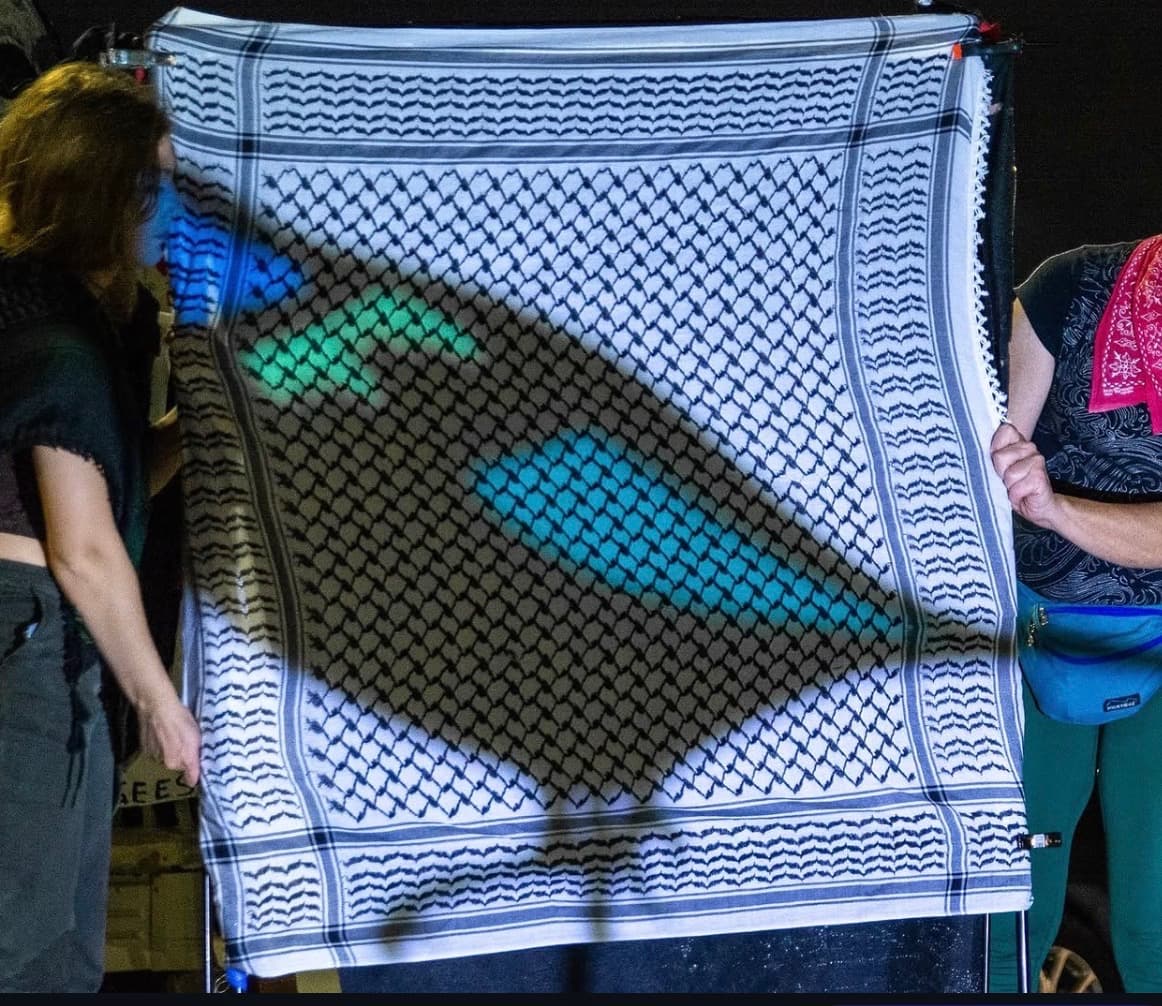 Shadow puppetry projected through a keffiyeh screen, showing colorful bird forms